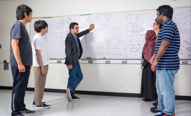 students standing while instructor whiteboards